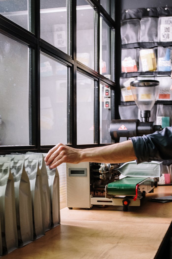 about-us A worker packs coffee bags in an industrial workshop setting with machinery.