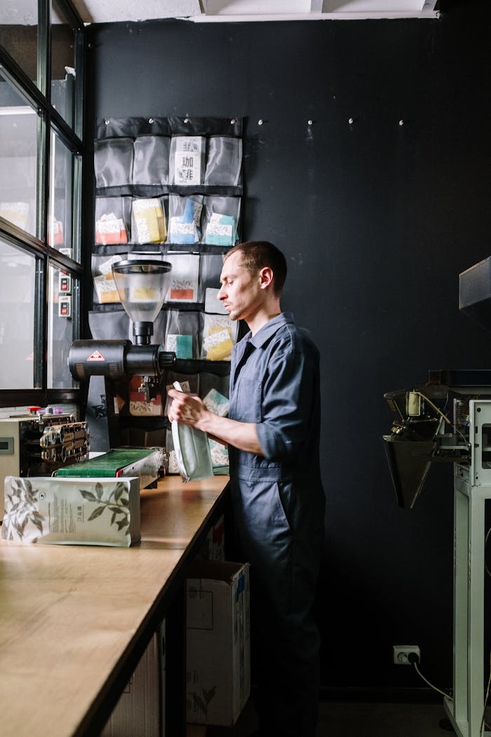 who-we-are A man in uniform works on coffee packaging in a modern coffee roasting workshop.